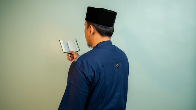 a Sheikh holding and reading the Holy Quran