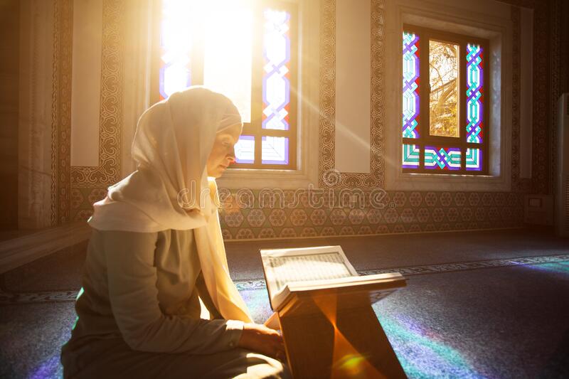 Young Muslim woman reads Quran under sunlight